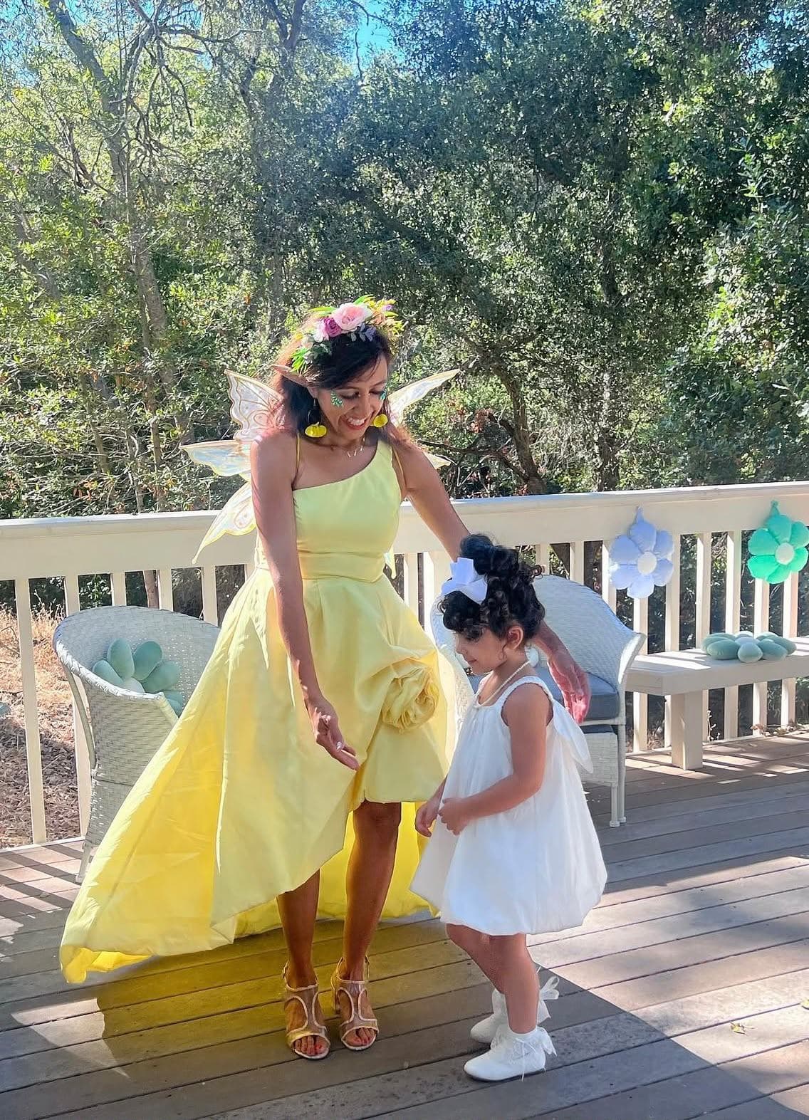 Fairy costumed entertainer with wings and a flower crown greeting a child at a garden themed birthday party