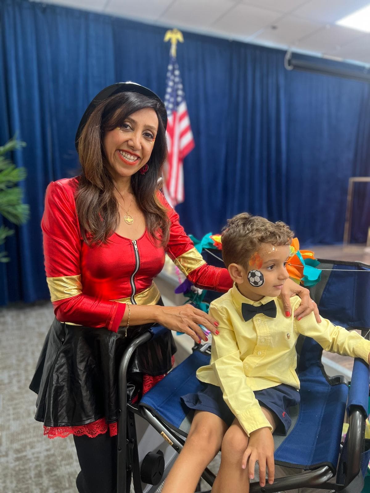 Superhero costumed host face painting a boy at an indoor kids event