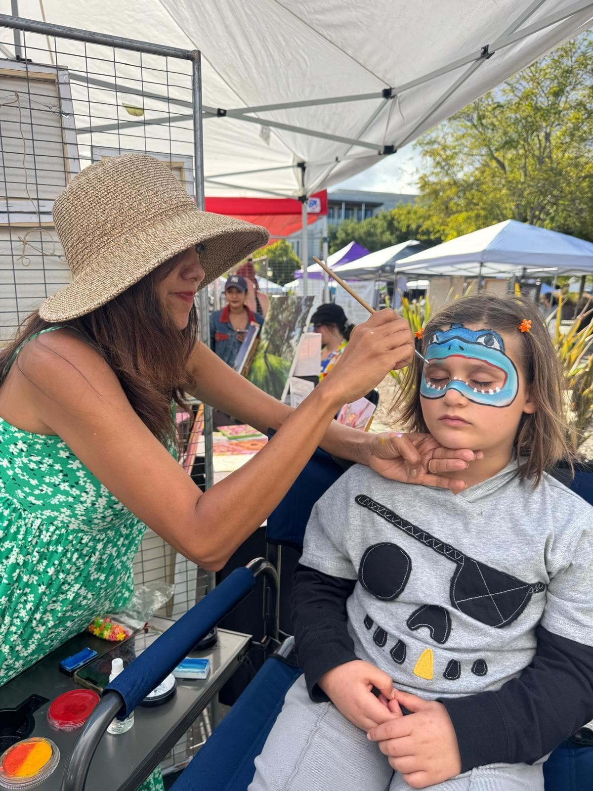 Superhero mask face painting in blue on a boy at a community event